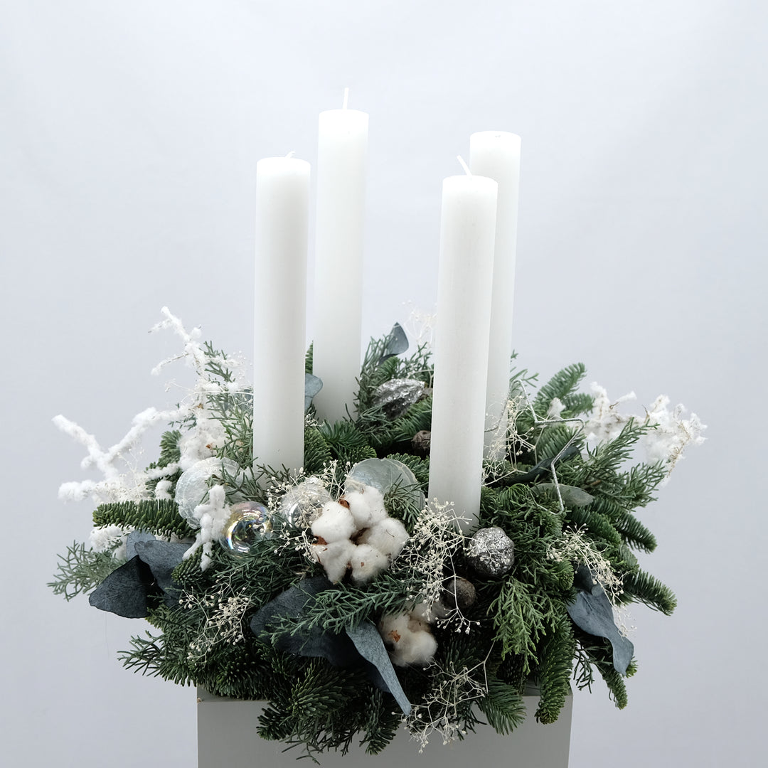 Winterlicher Adventskranz mit hohen Kerzen in Weiß