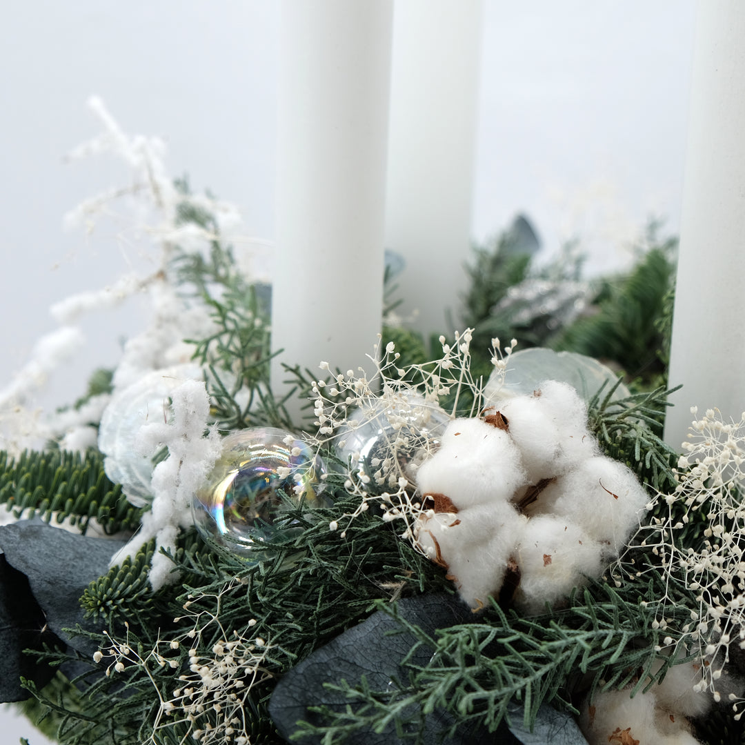 Winterlicher Adventskranz mit hohen Kerzen in Weiß